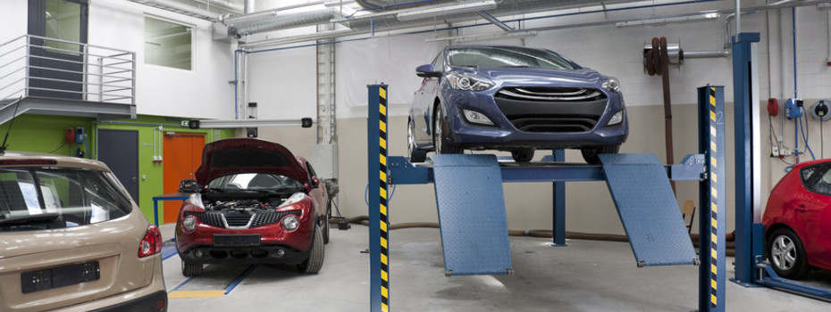 Cars in a large repair workshop or garage.